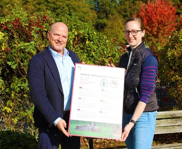 Hauptamtlicher Kreisbeigeordneter Christian Zuckermann und Amtstier�rztin Dr. Lara Stein mit Plakat zur Afrikanischen Schweinepest