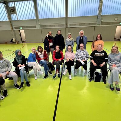 �bungsleiterausbildung f�r Menschen aus aller Welt - Gruppenbild: Tarik Mouhib vom Integrationsamt der Stadt Gie�en (hinten v.l.), Sportdezernent, Sportdezernent Christopher Lipp, Integrationskoordinatorin Lisa Fett und Sportkreisvorsitzender Heinz Zielinski und die Teilnehmenden in der Turnhalle der K�the-Kollwitz-Schule in Gie�en.