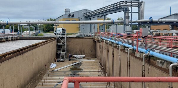 Das Bild zeigt die eine H�lfte des geleerten �Belebungsbecken Nr. 3� am Gie�ener Kl�rwerk w�hrend der Neumontage des effizienten Bel�ftersystemes und der Zuluftleitungen. Im Hintergrund (gelbes Geb�ude): Blockheizkraftwerk- und Verdichterstation, die die Energie zur Sauerstoff-Einbringung in die Belebungsbecken erzeugen.