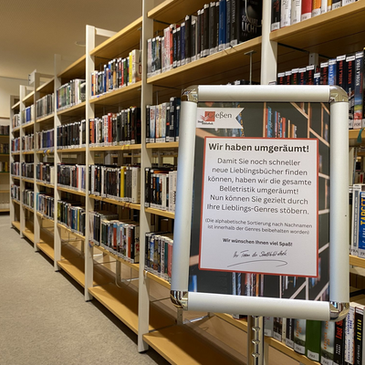 Bcherregal in der Stadtbibliothek mit Hinweisschild "Wir haben umgerumt"