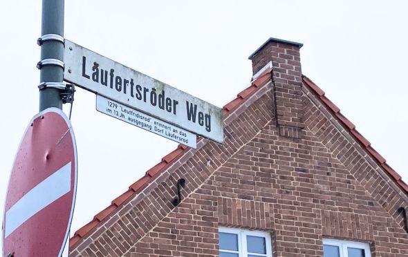 Stra&szlig;enschild L&auml;ufertsr&ouml;der Weg mit Giebel eine Backsteinhauses in der Weststadt im Hintergrund