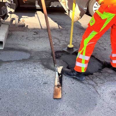 Bei einem tiefen Schlagloch wird die erste Asphaltschicht festgestampft, ehe die zweite Schicht mit der R�ttelmaschine befestigt wird.