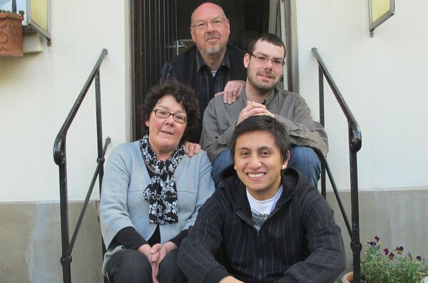 Eine Gastfamilie sitzt mit Austauschsch&uuml;ler auf ewiner Treppe vor dem Haus