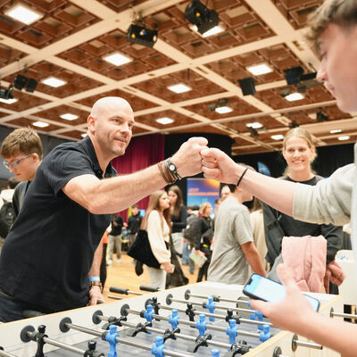 Zwei Menschen begr&uuml;&szlig;en sich beim Tischkicker spielen