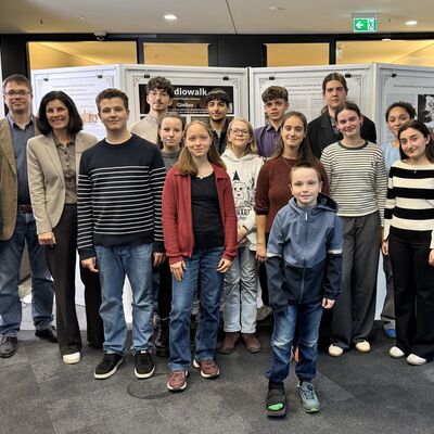 Gruppenfoto im April 2026 im Anschluss an die Er�ffnung der Plakatausstellung zum Geschichtswettbewerb in der Sparkasse Gie�en - v. l. n. r.; Tutorin Sabine Schneider, Stadtarchivar Christian P�pken, Vorstandsmitglied der Sparkasse und Gastgeberin Ilona Roth, Sch�lerinnen und Sch�ler sowie Oberb�rgermeister Frank-Tilo Becher.