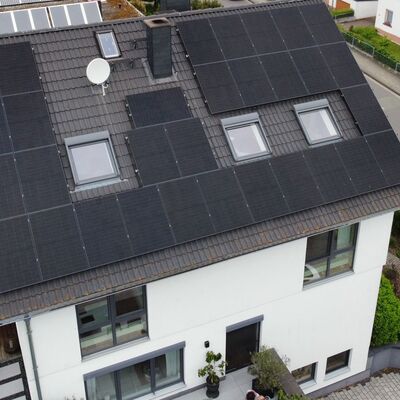 Luftaufnahme eines Wohnhauses mit Photovoltaik-Modulen auf dem Dach