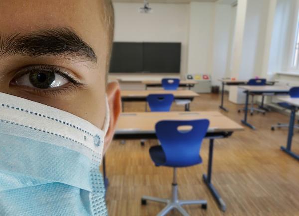 Leerer Klassenraum und Schler mit Mund-Nasen-Maske