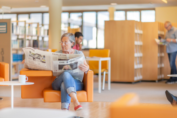 Zeitung lesende Frau in der Stadtbibliothek