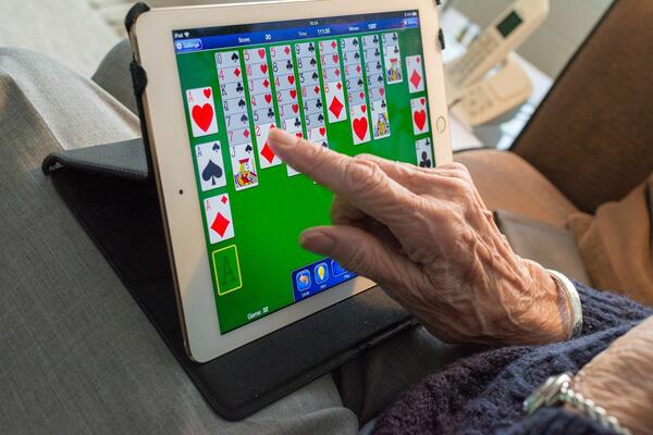 Die Hand einer Seniorin bedient ein Tablet