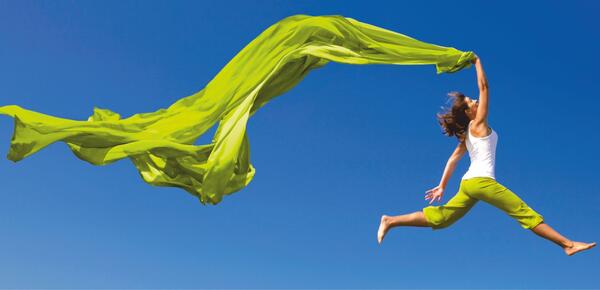Eine Frau springt in die Luft und zieht ein Tuch hinter sich her