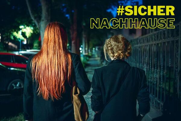 Zwei Frauen laufen bei Dunkelheit �ber einen Gehweg | Text "#SICHER NACHHAUSE"