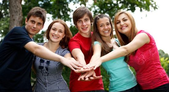 Kleine Gruppe Jugendliche halten Hände zusammen